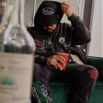 Person sitting on a couch in dutch pat Ernz baseball hat with a red cup in hand
